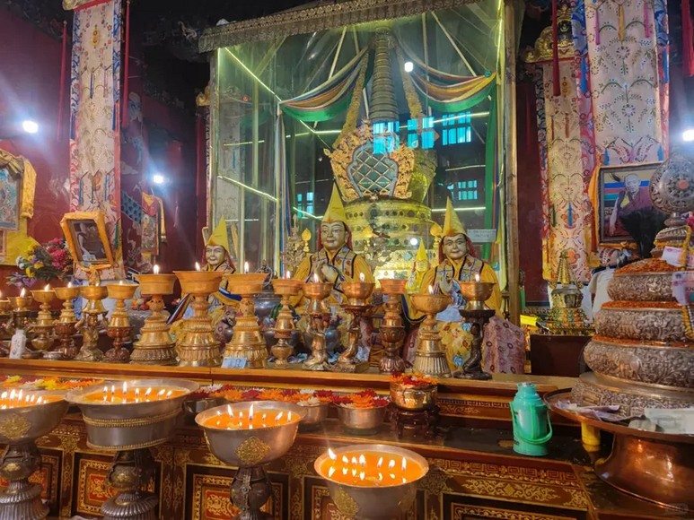 Bên trong một chính điện tu viện Tây Tạng với đèn bơ và tượng Phật